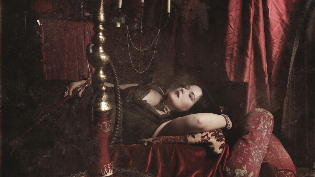 Photo of a model lying down with a sisha in a burlesque setting.